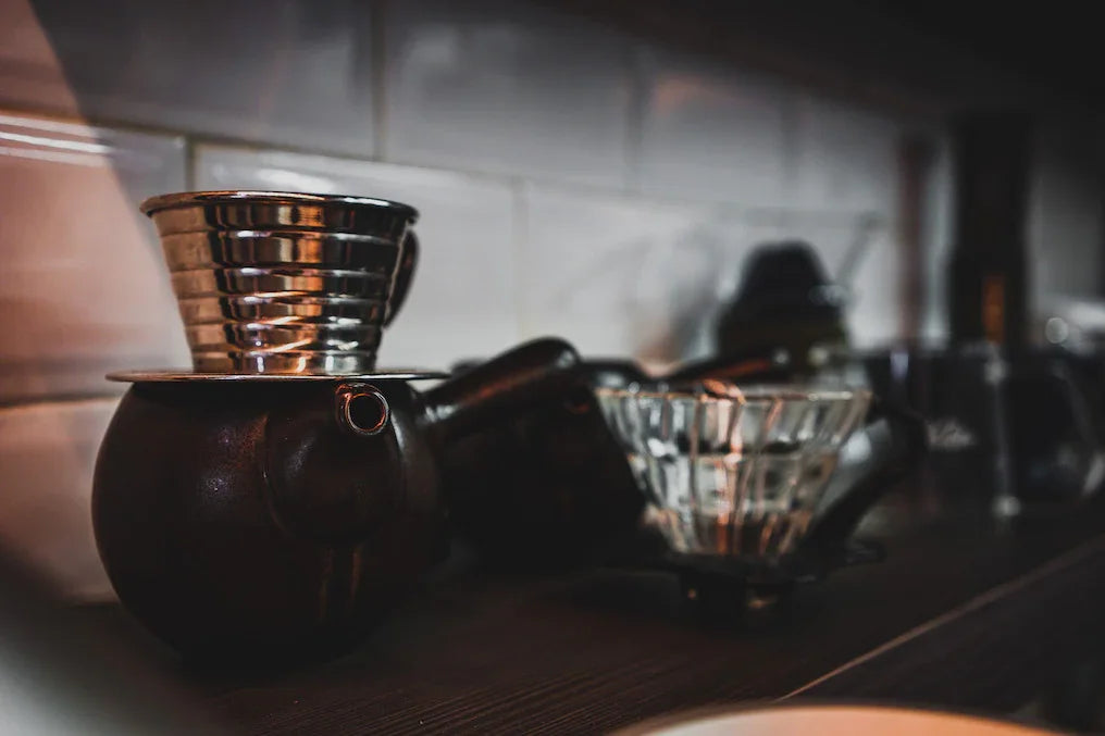 Vietnamese coffee dripper on dark ceramic pot, specialty coffee brewing setup in cozy café