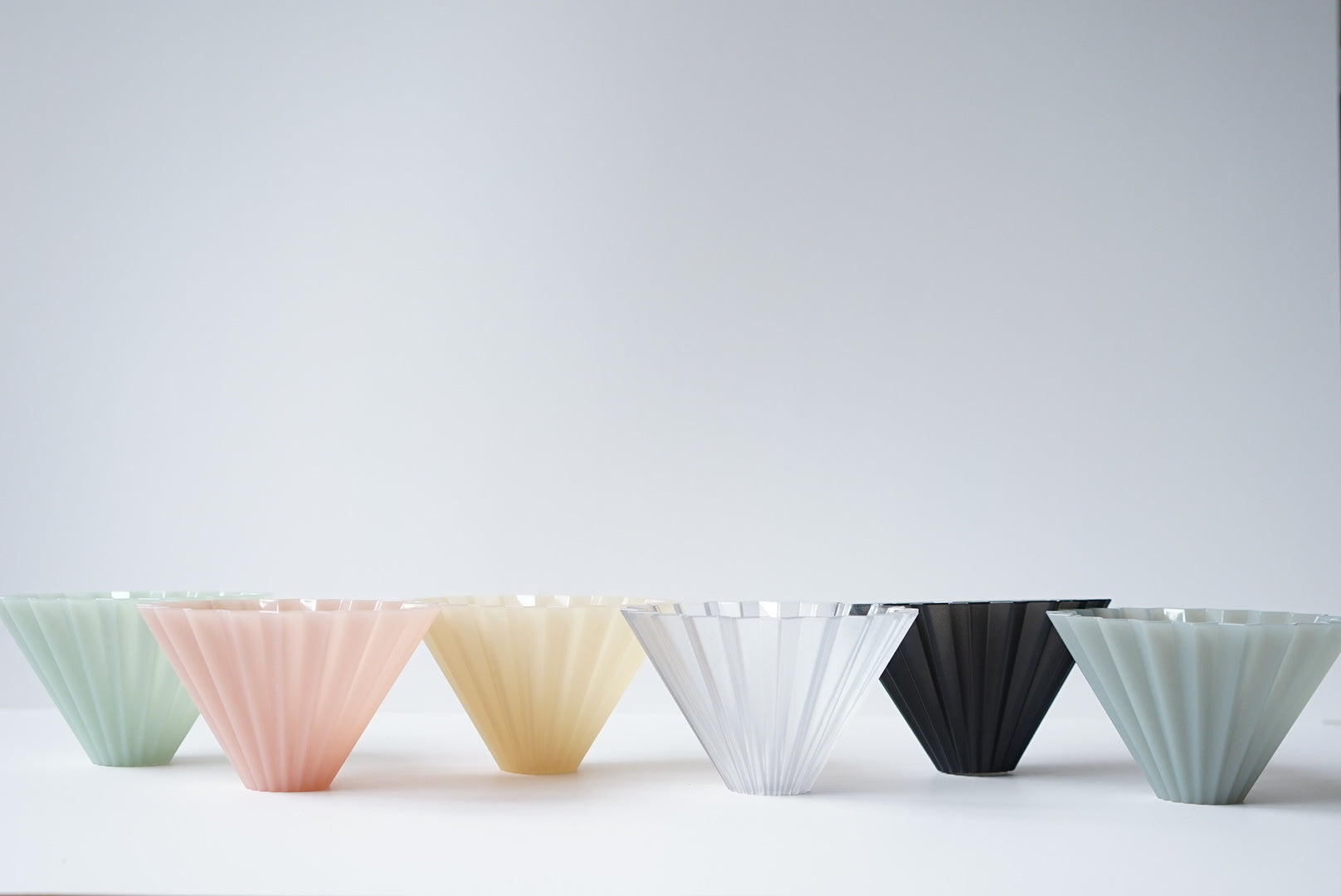 Six colorful pour-over coffee filters in pastel and black, ideal for specialty brews and filter coffee.